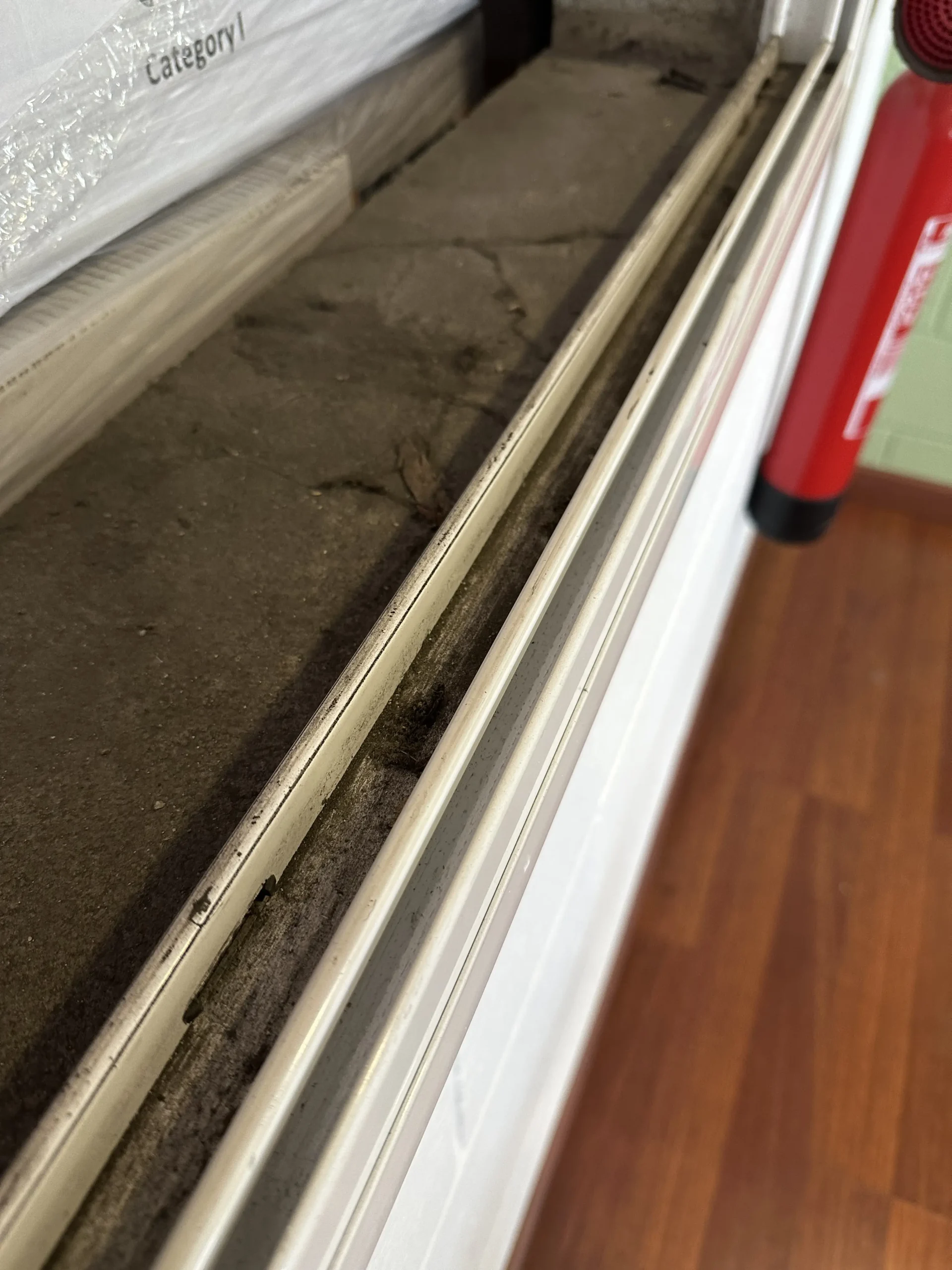 Riel de ventana con polvo acumulado antes de la limpieza fin de obra